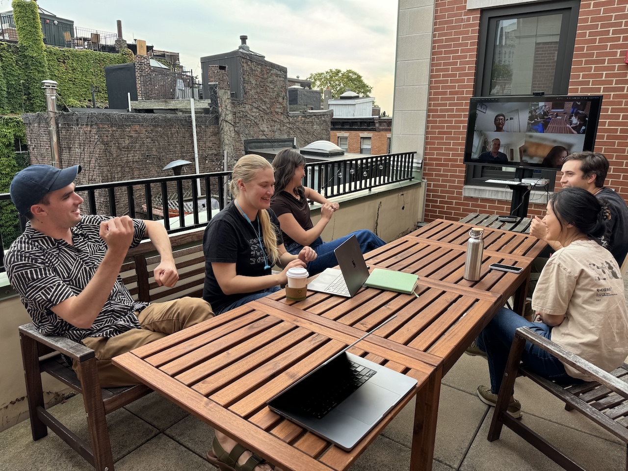 A group of people sitting around a long wooden table on a patio
