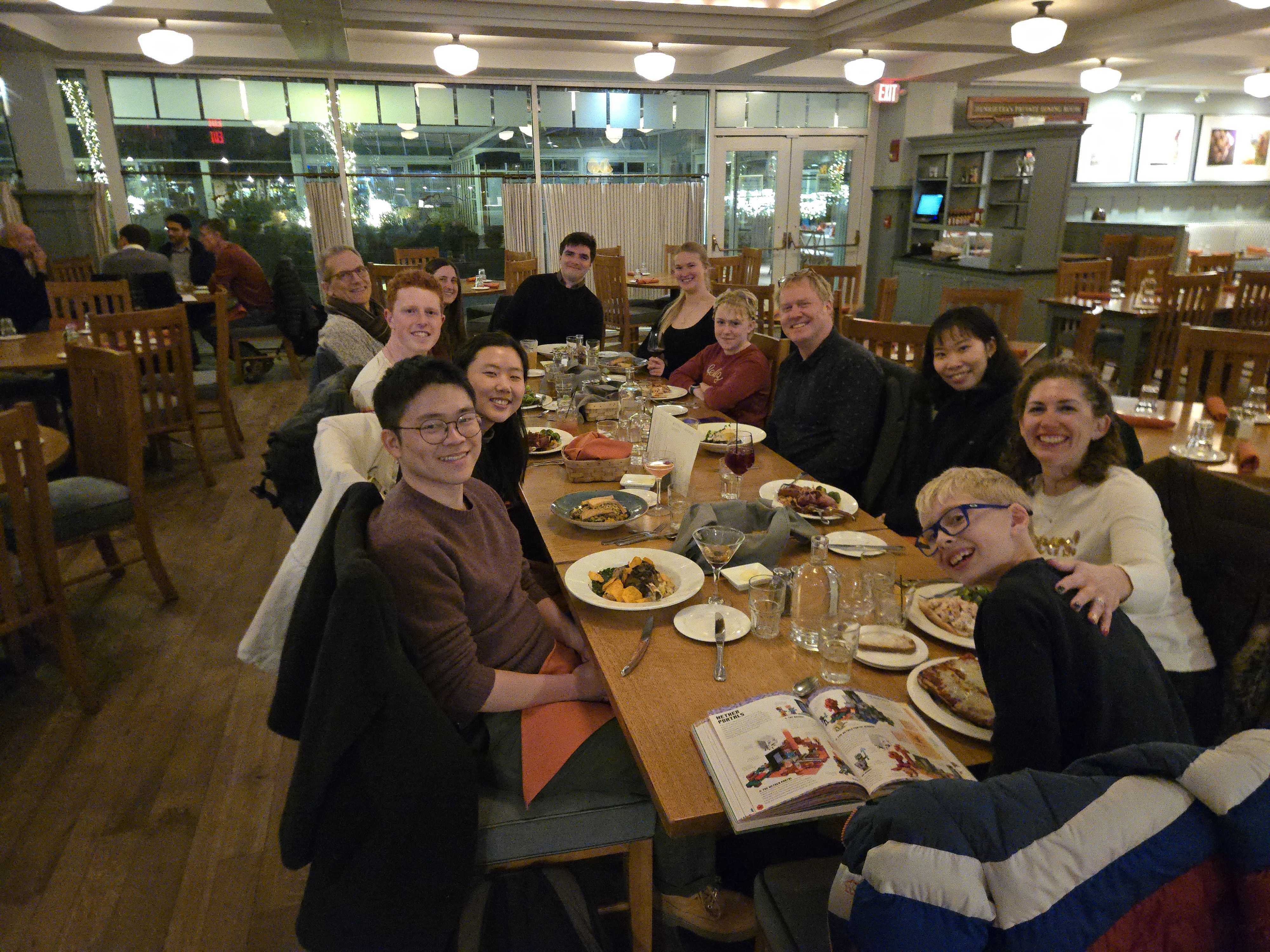 A group of people sitting around a long wooden table for dinner