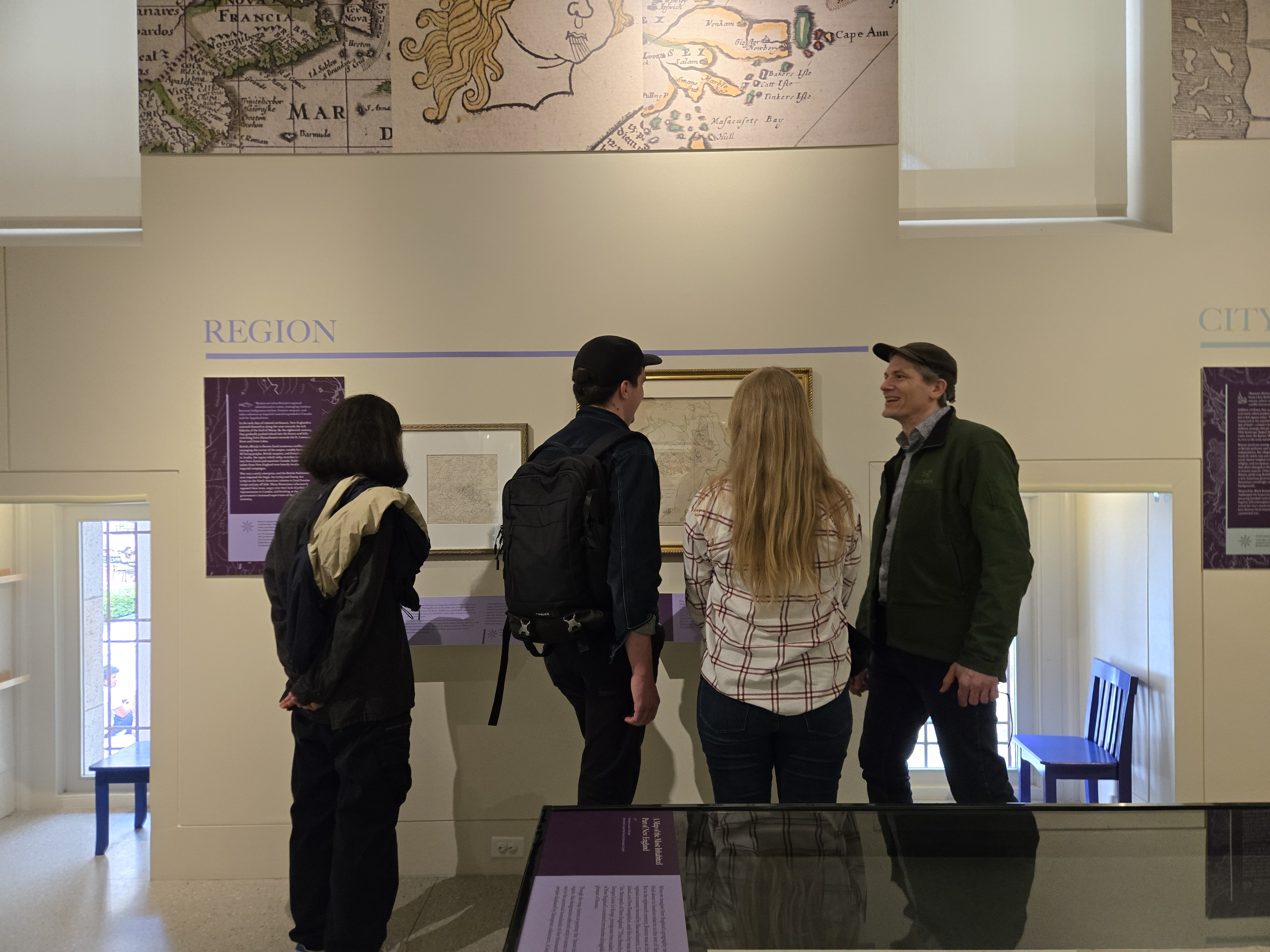 Fathomites talk in front of old world maps at the Leventhal Map & Education Center.